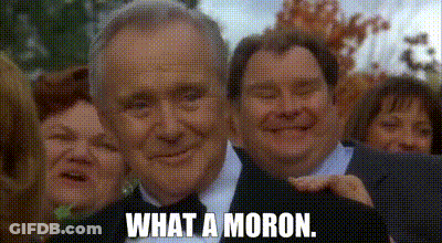 A Man In A Suit And Tie Is Smiling In Front Of A Group Of People . GIF