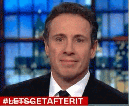 A Man In A Suit And Tie Is Smiling In Front Of A Screen That Says #Letsgetafterit GIF