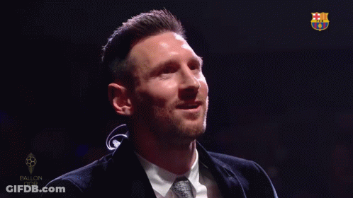 A Man In A Suit And Tie Is Smiling In Front Of A Sign That Says Ballon Dor GIF