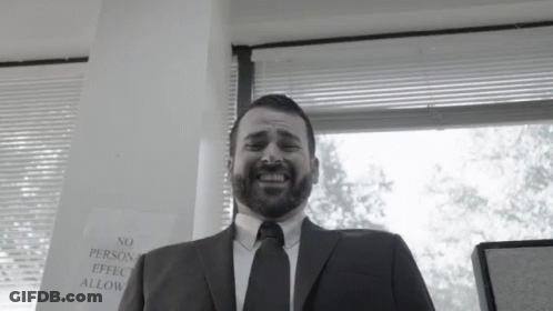 A Man In A Suit And Tie Is Smiling In Front Of A Sign That Says No Person Effect Allow GIF