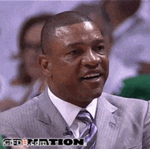 A Man In A Suit And Tie Is Smiling In Front Of A Sign That Says Sbnation GIF