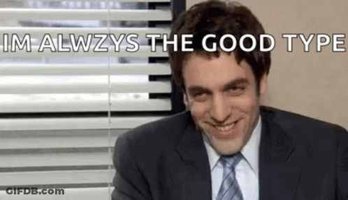 A Man In A Suit And Tie Is Smiling In Front Of A Window With Blinds . GIF