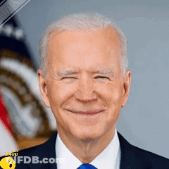 A Man In A Suit And Tie Is Smiling In Front Of An American Flag . GIF