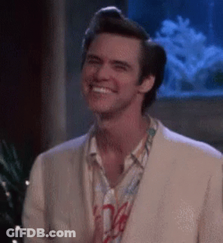A Man In A Suit And Tie Is Smiling In Front Of An Aquarium . GIF