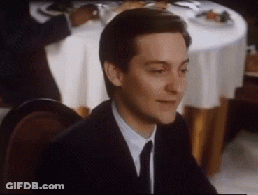 A Man In A Suit And Tie Is Smiling While Sitting At A Table . GIF