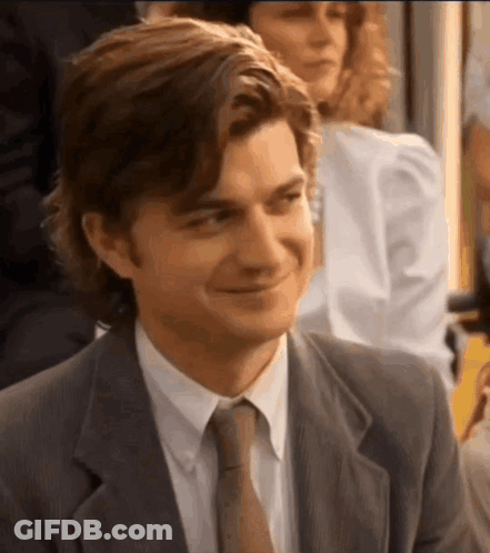 A Man In A Suit And Tie Is Smiling While Sitting In A Room . GIF
