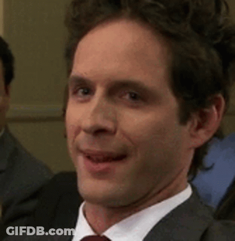 A Man In A Suit And Tie Is Smiling While Sitting In A Room . GIF