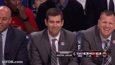 A Man In A Suit And Tie Is Smiling While Sitting In The Stands During A Basketball Game GIF