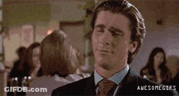 A Man In A Suit And Tie Is Smiling While Standing In A Crowded Room . GIF