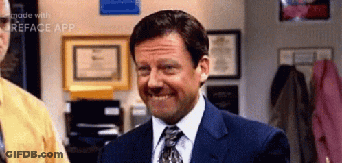 A Man In A Suit And Tie Is Smiling While Standing In A Room . GIF