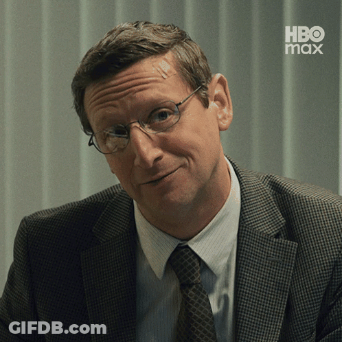 A Man In A Suit And Tie Is Smiling With A Hbo Max Logo In The Background GIF