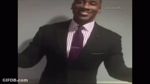 A Man In A Suit And Tie Is Smiling With His Arms Outstretched . GIF