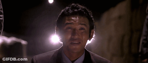 A Man In A Suit And Tie Is Smiling With His Hand Outstretched GIF