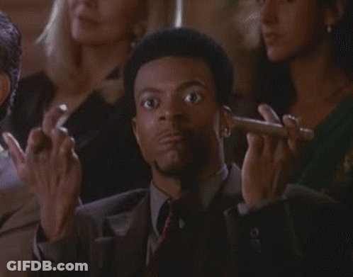 A Man In A Suit And Tie Is Smoking A Cigar In A Crowd Of People GIF