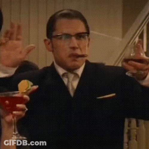 A Man In A Suit And Tie Is Smoking A Cigar While Holding A Martini Glass . GIF