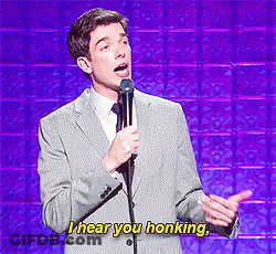 A Man In A Suit And Tie Is Speaking Into A Microphone And Says I Hear You Honking GIF