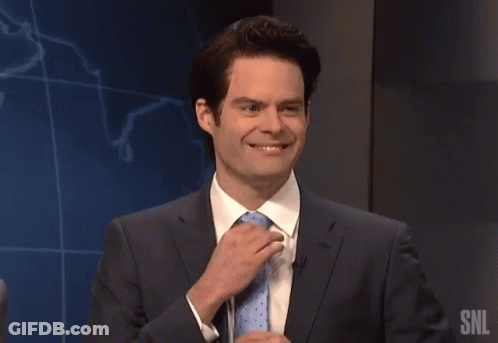 A Man In A Suit And Tie Is Speaking Into A Microphone With The Snl Logo In The Background GIF