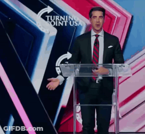 A Man In A Suit And Tie Is Standing At A Podium In Front Of A Turning Point Usa Sign GIF