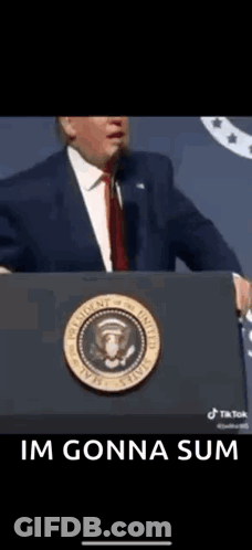 A Man In A Suit And Tie Is Standing At A Podium With The Words `` Im Gonna Sum '' Below Him . GIF