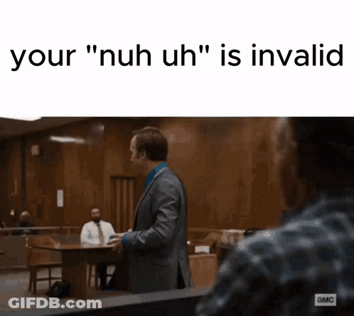 A Man In A Suit And Tie Is Standing In A Courtroom And Talking To Another Man Sitting At A Table . GIF