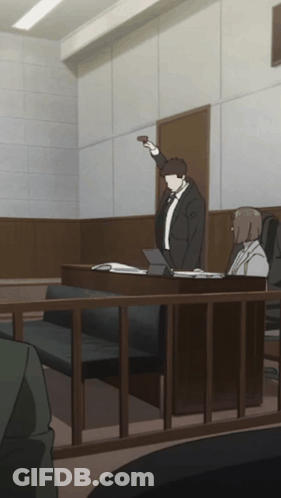 A Man In A Suit And Tie Is Standing In A Courtroom Holding Up A Gun GIF