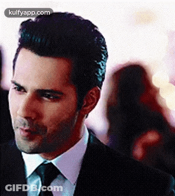A Man In A Suit And Tie Is Standing In A Crowd . GIF