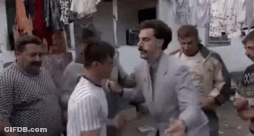 A Man In A Suit And Tie Is Standing In A Crowd Of Men . GIF