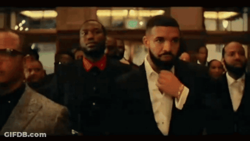 A Man In A Suit And Tie Is Standing In A Crowd Of People . GIF