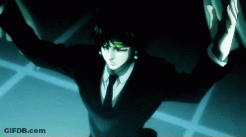 A Man In A Suit And Tie Is Standing In A Dark Room GIF