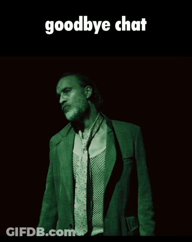 A Man In A Suit And Tie Is Standing In A Dark Room Under A Goodbye Chat Sign GIF