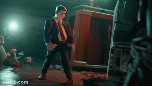 A Man In A Suit And Tie Is Standing In A Dark Room With A TV In The Background GIF