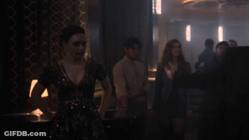 A Man In A Suit And Tie Is Standing In A Dark Room GIF