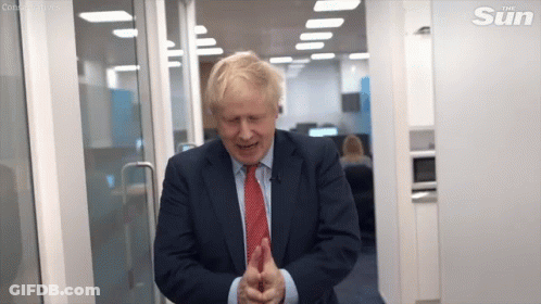 A Man In A Suit And Tie Is Standing In A Doorway And Smiling . GIF