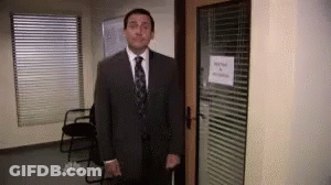 A Man In A Suit And Tie Is Standing In A Doorway Holding A Cane . GIF