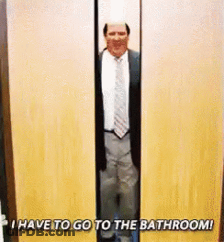 A Man In A Suit And Tie Is Standing In A Doorway With The Words `` I Have To Go To The Bathroom ! '' GIF