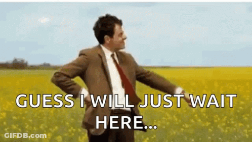 A Man In A Suit And Tie Is Standing In A Field Of Yellow Flowers And Says `` Guess I Will Just Wait Here ... '' GIF