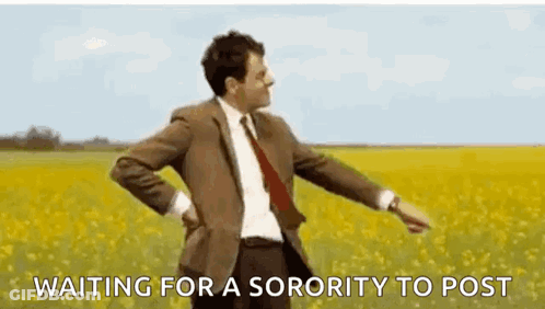 A Man In A Suit And Tie Is Standing In A Field Of Yellow Flowers And Waiting For A Sorority To Post . GIF