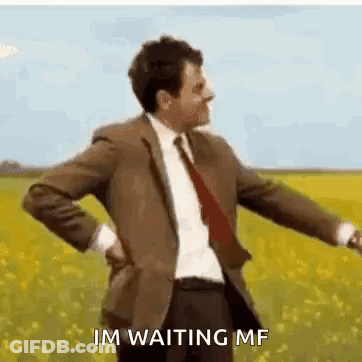 A Man In A Suit And Tie Is Standing In A Field With His Hands On His Back . GIF