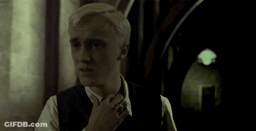 A Man In A Suit And Tie Is Standing In A Hallway . GIF