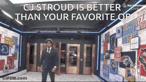 A Man In A Suit And Tie Is Standing In A Hallway With A Sign That Says Cj Stroud GIF