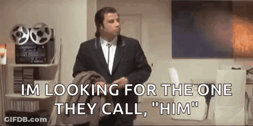 A Man In A Suit And Tie Is Standing In A Living Room And Talking To Someone . GIF