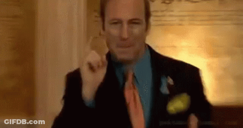 A Man In A Suit And Tie Is Standing In A Room . GIF