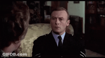 A Man In A Suit And Tie Is Standing In A Room And Making A Funny Face . GIF