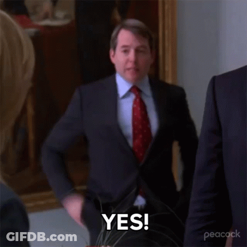 A Man In A Suit And Tie Is Standing In A Room And Says Yes . GIF