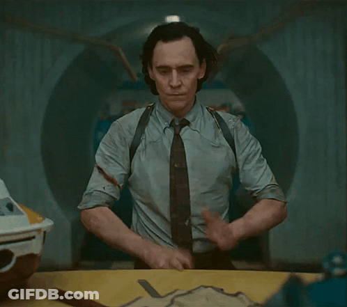 A Man In A Suit And Tie Is Standing In A Room GIF