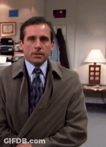 A Man In A Suit And Tie Is Standing In A Room With A Lamp GIF