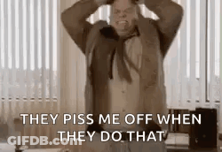 A Man In A Suit And Tie Is Standing In A Room With His Hands On His Head And Screaming . GIF