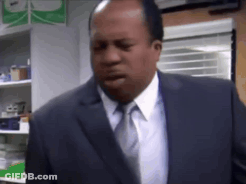 A Man In A Suit And Tie Is Standing In A Room With His Mouth Open . GIF