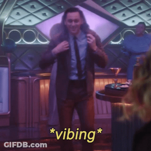 A Man In A Suit And Tie Is Standing In A Room With The Words * Vibing * On The Bottom GIF