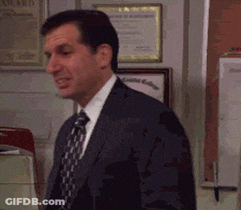 A Man In A Suit And Tie Is Standing In An Office . GIF
